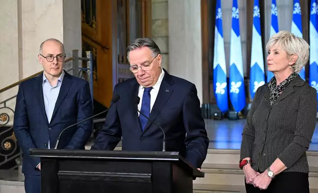 Quebec Premier Francois Legault, accompanied by his chief of staff Martin Koskinen, left, and wife Isabelle Brais, right, pauses as he announces his resignation in Quebec City, on Wednesday, Jan. 14, 2026. (Jacques Boissinot/The Canadian Press via AP)