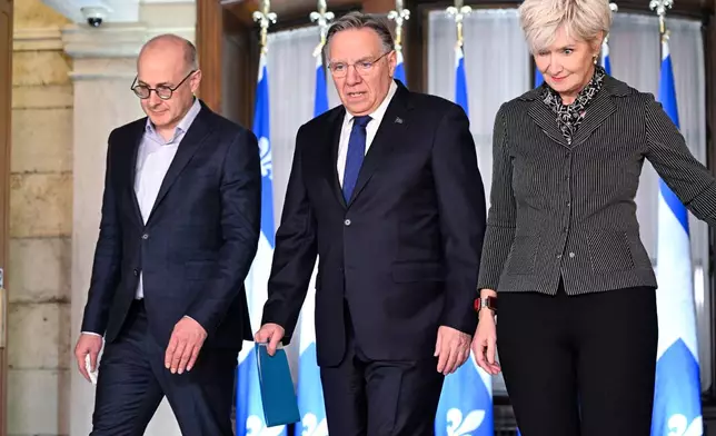 Quebec Premier Francois Legault, accompanied by his chief of staff Martin Koskinen, left, and wife Isabelle Brais, right, walk to a news conference to announce his resignation in Quebec City, on Wednesday, Jan. 14, 2026. (Jacques Boissinot/The Canadian Press via AP)