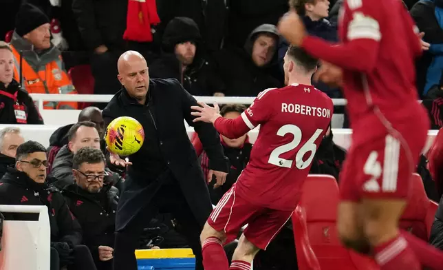 Liverpool's manager Arne Slot, left, passes the ball to Liverpool's Andrew Robertson during the English Premier League soccer match between Liverpool and Leeds United in Liverpool, England, Thursday, Jan. 1, 2026. (AP Photo/Jon Super)