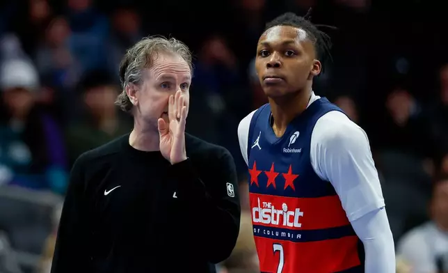 Washington Wizards head coach Brian Keefe, left, talks to guard Bub Carrington during the first half of an NBA basketball game against the Charlotte Hornets in Charlotte, N.C., Saturday, Jan. 24, 2026. (AP Photo/Nell Redmond)