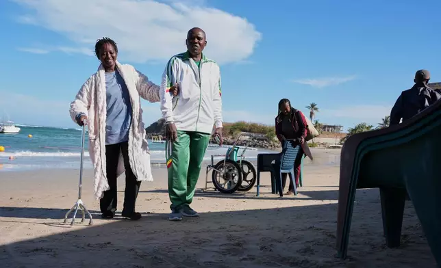 FILE - A woman walks with a relative after an aquatic therapy session in Dakar, Senegal, Saturday, Dec. 13, 2025. (AP Photo/Misper Apawu, File)