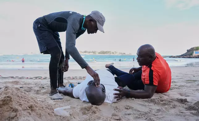 FILE - Instructors help a participant exercise at the beach shore in Dakar, Senegal, Saturday, Dec. 13, 2025. (AP Photo/Misper Apawu, File)