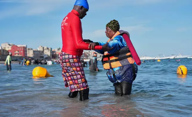 FILE - An instructor assists a participant with limited mobility out of the ocean after an aquatic therapy session in Dakar, Senegal, Saturday, Dec. 13, 2025. (AP Photo/Misper Apawu, File)
