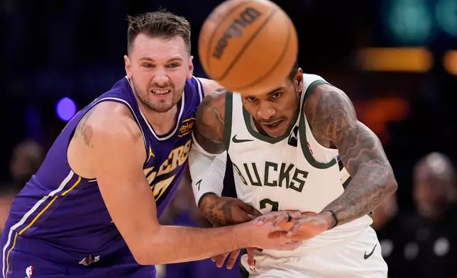 Los Angeles Lakers guard Luka Doncic, left, and Milwaukee Bucks guard Kevin Porter Jr. go after a loose ball during the first half of an NBA basketball game Friday, Jan. 9, 2026, in Los Angeles. (AP Photo/Mark J. Terrill)