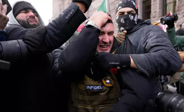 Jake Lang, center, who organized the protest March Against Minnesota Fraud, clutches his head as he leaves the rally near Minneapolis City Hall, Saturday, Jan. 17, 2026, in Minneapolis. (AP Photo/Yuki Iwamura)