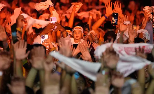 Catholic devotees raise their hands and wave white towels as a carriage carrying the image of Jesus Nazareno passes by during its annual procession in Manila, Philippines, on its feast day Friday Jan. 9, 2026. (AP Photo/Aaron Favila)