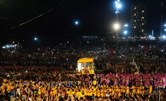 Catholic devotees walk beside a glass-covered carriage carrying the image of Jesus Nazareno during its annual procession in Manila, Philippines, on its feast day, Friday Jan. 9, 2026. (AP Photo/Aaron Favila)