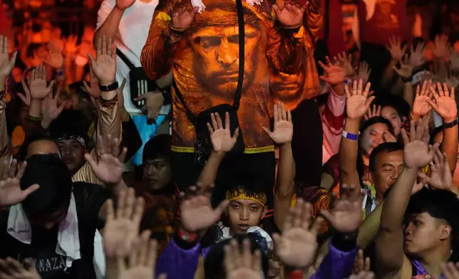 Catholic devotees raise their hands as a carriage carrying the image of Jesus Nazareno passes by during its annual procession in Manila, Philippines, on its feast day Friday Jan. 9, 2026. (AP Photo/Aaron Favila)