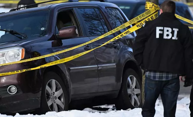 A bullet hole is seen in the windshield as law enforcement officers attend to the scene of the shooting involving federal law enforcement agents, Wednesday, Jan. 7, 2026, in Minneapolis. (AP Photo/Tom Baker)