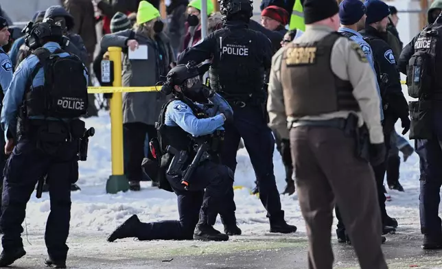 Law enforcement officers attend to the scene of the shooting involving federal law enforcement agents, Wednesday, Jan. 7, 2026, in Minneapolis. (AP Photo/Tom Baker)