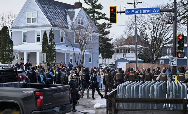 People protest as law enforcement officers attend to the scene of the shooting involving federal law enforcement agents, Wednesday, Jan. 7, 2026, in Minneapolis. (AP Photo/Tom Baker)
