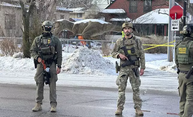 Federal law enforcement officers stand near a roadblock at Portland Avenue and East 32nd Street, Wednesday, Jan. 7, 2026, after reports of a shooting involving federal agents in Minneapolis, where immigration enforcement has been conducting a major crackdown. (AP Photo/Tim Sullivan)