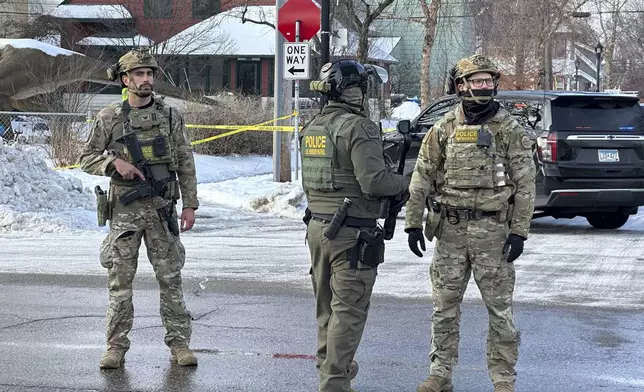 Federal law enforcement officers stand near a roadblock at Portland Avenue and East 32nd Street, Wednesday, Jan. 7, 2026, after reports of a shooting involving federal agents in Minneapolis, where immigration enforcement has been conducting a major crackdown. (AP Photo/Tim Sullivan)