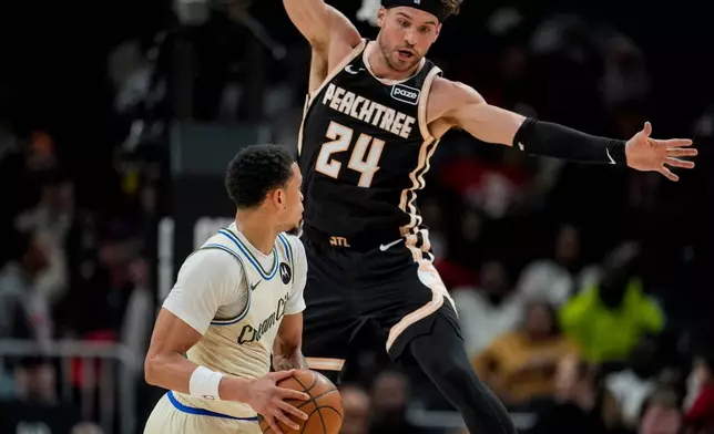 Milwaukee Bucks guard Ryan Rollins (13) looks to pass against Atlanta Hawks forward Corey Kispert (24) during the first half of an NBA basketball game, Monday, Jan. 19, 2026, in Atlanta. (AP Photo/Mike Stewart)