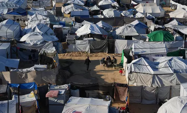 Displaced Palestinians gather outside a tent at a temporary camp in Deir al-Balah, central Gaza Strip, Saturday, Jan. 17, 2026. (AP Photo/Abdel Kareem Hana)