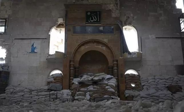 Sandbag barriers used as fighting positions by Kurdish fighters, left inside a destroyed mosque in the Sheikh Maqsoud neighborhood, where clashes between government forces and Kurdish fighters have been taking place in the northern city of Aleppo, Syria, Sunday, Jan. 11, 2026. (AP Photo/Ghaith Alsayed)