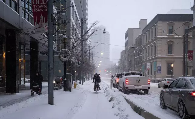 A cargo cyclist rides along Adelaide Street East amid heavy snowfall and accumulation as snow and heavy winds continue to hammer the Greater Toronto Area, in Toronto, Thursday, Jan. 15, 2026. (Giordano Ciampini /The Canadian Press via AP)
