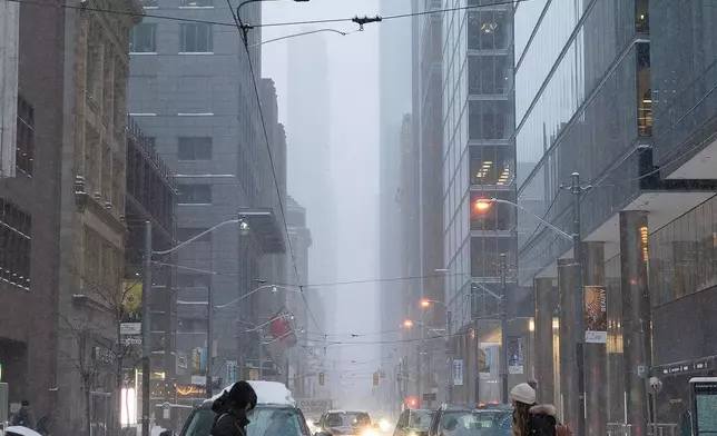 Pedestrians cross Adelaide Street along Yonge Street amid heavy snowfall and accumulation as snow and heavy winds continue to hammer the Greater Toronto Area, in Toronto, Thursday, Jan. 15, 2026. (Giordano Ciampini /The Canadian Press via AP)