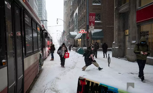 Commuters make their way to their destinations on King Street East amid heavy snowfall and accumulation as snow and heavy winds continue to hammer the Greater Toronto Area, in Toronto, Thursday, Jan. 15, 2026. (Giordano Ciampini /The Canadian Press via AP)