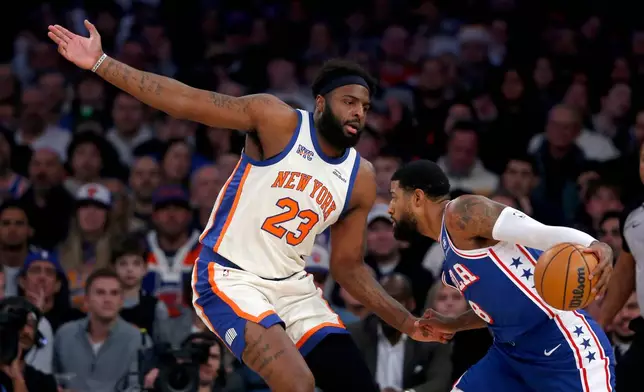 New York Knicks center Mitchell Robinson, left, defends Philadelphia 76ers forward Paul George, right, during the first half of an NBA basketball game, Saturday, Jan. 3, 2026, in New York. (AP Photo/John Munson)