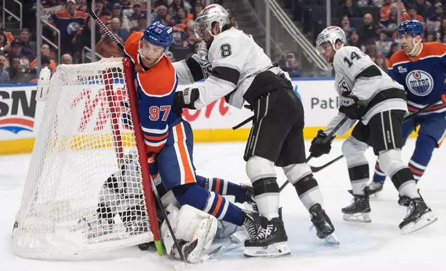 Los Angeles Kings' Drew Doughty (8) checks Edmonton Oilers' Connor McDavid (97) into the net during an overtime of an NHL hockey game in Edmonton on Saturday, Jan. 10, 2026. (Jason Franson/The Canadian Press via AP)