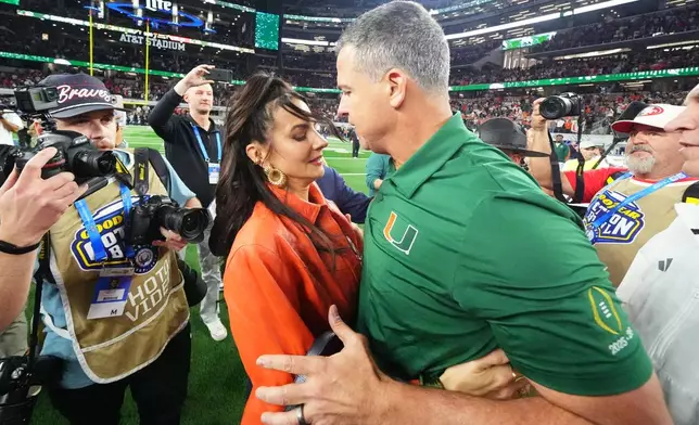 Miami head coach Mario Cristobal, right, talks to his wife, Jessica Cristobal, following the Cotton Bowl College Football Playoff quarterfinal game against Ohio State Wednesday, Dec. 31, 2025, in Arlington, Texas. (AP Photo/Julio Cortez)