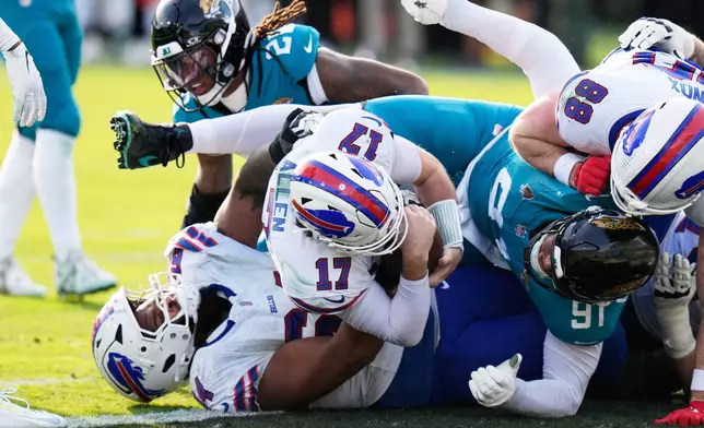 Buffalo Bills quarterback Josh Allen (17) pushes in for a first down as Jacksonville Jaguars defensive tackle Arik Armstead (91) tries to stop him during the second half of an NFL wild-card playoff football game Sunday, Jan. 11, 2026, in Jacksonville, Fla. (AP Photo/Chris O'Meara)
