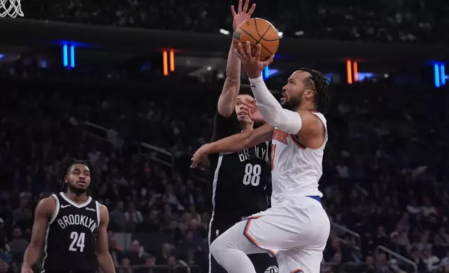 New York Knicks' Jalen Brunson, right, drives past Brooklyn Nets' Nolan Traore, center, as Cam Thomas, left, watches during the first half of an NBA basketball game Wednesday, Jan. 21, 2026, in New York. (AP Photo/Frank Franklin II)