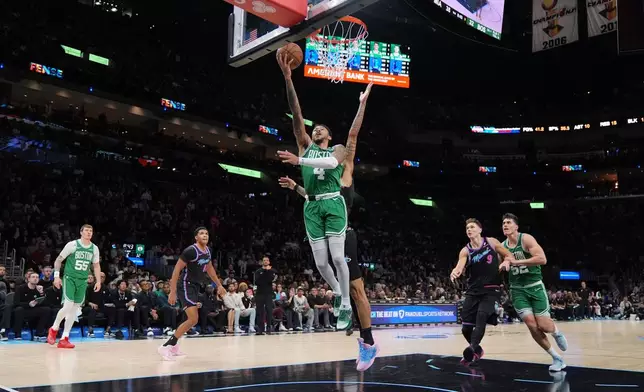 Boston Celtics guard Anfernee Simons (4) goes for the basket defended by Miami Heat center Kel'el Ware, obscured, during the first half of an NBA basketball game, Thursday, Jan. 15, 2026, in Miami. (AP Photo/Rebecca Blackwell)