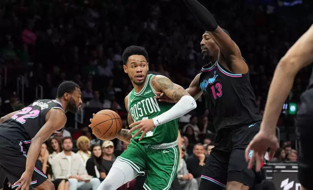 Boston Celtics guard Anfernee Simons, center, is defended by Miami Heat center Bam Adebayo (13) during the first half of an NBA basketball game, Thursday, Jan. 15, 2026, in Miami. (AP Photo/Rebecca Blackwell)