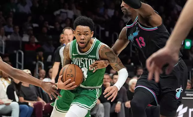 Boston Celtics guard Anfernee Simons (4) comes under pressure from Miami Heat center Bam Adebayo (13) during the first half of an NBA basketball game, Thursday, Jan. 15, 2026, in Miami. (AP Photo/Rebecca Blackwell)