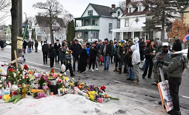 People gather around a makeshift memorial honoring the victim of a fatal shooting involving federal law enforcement agents, near the site of the shooting, Thursday, Jan. 8, 2026, in Minneapolis. (AP Photo/Tom Baker)