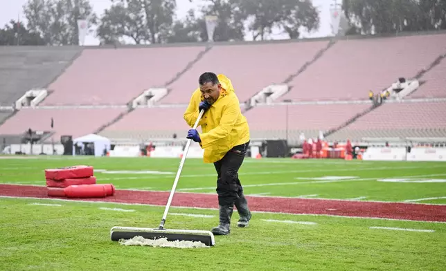 Workers clear rain water off the playing field before the Rose Bowl College Football Playoff quarterfinal game Thursday, Jan. 1, 2026, in Pasadena, Calif. (AP Photo/Kyusung Gong)