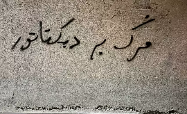 A slogan is written on a wall reading in Farsi: "Death to dictator" in an anti-government protest in Tehran, Iran, Saturday, Jan. 10, 2026. (AP Photo)