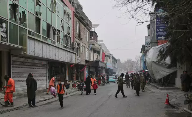 Workers clean the scene as Taliban police secure the area after an explosion at a Chinese restaurant, right, whose entrance is covered with blankets, killed at least seven people, including a Chinese national, a day earlier in Kabul, Afghanistan, Tuesday, Jan. 20, 2026. (AP Photo/Siddiqullah Alizai)