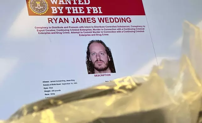 FILE - An image of former Canadian Olympic snowboarder Ryan Wedding, who is a fugitive and been charged with allegedly running and participating in a transnational drug trafficking operation, is displayed on a video monitor along with bricks of cocaine, foreground, during a news conference at the FBI offices in Los Angeles, Oct. 17, 2024. (AP Photo/Damian Dovarganes, File)