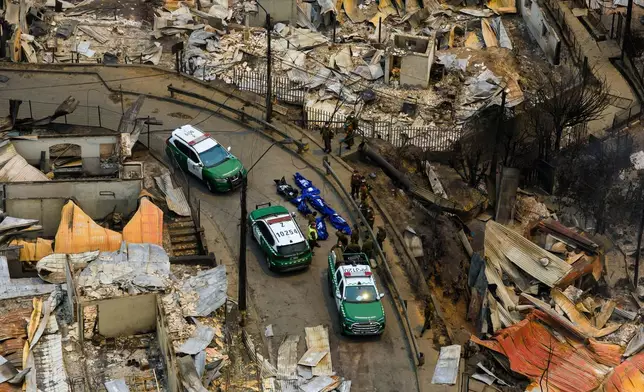 Police recover the bodies of people who died after wildfires swept through homes near Lirquen, Chile, Sunday, Jan. 18, 2026. (AP Photo/Javier Torres)