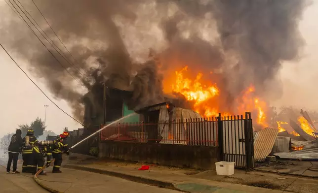 Firefighters battle a blaze at a house as wildfires burn in Lirquen, Chile, Sunday, Jan. 18, 2026. (AP Photo/Javier Torres)