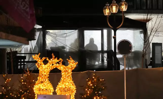 Shadows of People are seen in the sealed off Le Constellation bar, where a devastating fire left dead and injured during the New Year's celebrations in Crans-Montana, Swiss Alps, Switzerland, Thursday, Jan. 1, 2026. (AP Photo/ Antonio Calanni)