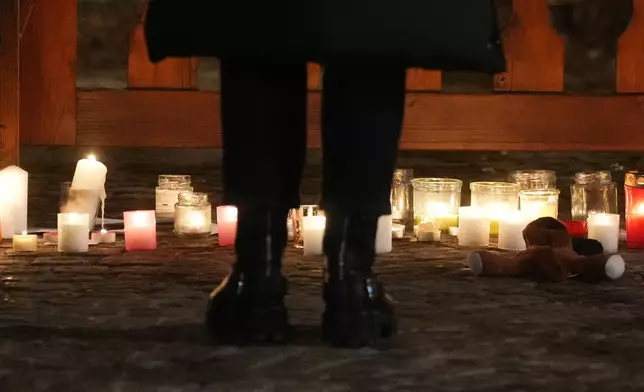 People lay candles and flowers near the Le Constellation bar, where a devastating fire left dead and injured during the New Year's celebrations in Crans-Montana, Swiss Alps, Switzerland, Thursday, Jan. 1, 2026. (AP Photo/ Antonio Calanni)