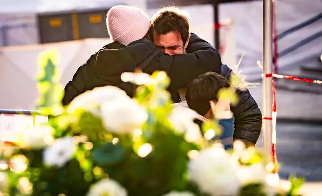 People cry at the scene after a fire broke out at the "Le Constellation" bar and lounge during New Year's celebration, in Crans-Montana, Switzerland, Thursday, Jan. 1, 2026. (Jean-Christophe Bott/Keystone via AP)
