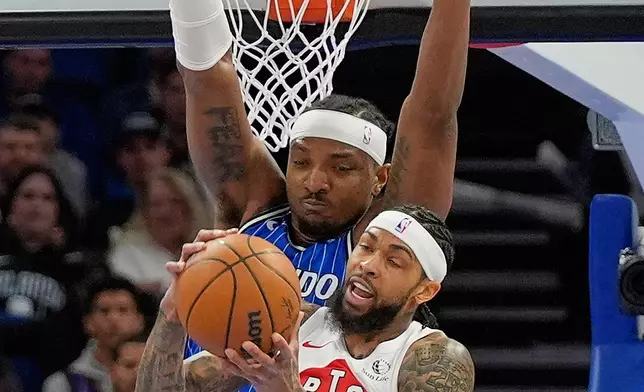 Toronto Raptors forward Brandon Ingram, right, tries to get in position for a shot against Orlando Magic center Wendell Carter Jr. during the first half of an NBA basketball game, Friday, Jan. 30, 2026, in Orlando, Fla. (AP Photo/John Raoux)