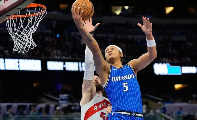 Orlando Magic forward Paolo Banchero (5) shoots over Toronto Raptors forward Sandro Mamukelashvili, left, during the first half of an NBA basketball game, Friday, Jan. 30, 2026, in Orlando, Fla. (AP Photo/John Raoux)