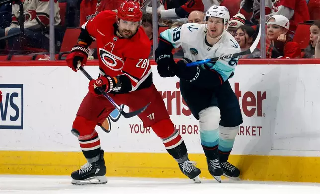 Carolina Hurricanes' William Carrier (28) clears the puck from Seattle Kraken's Ben Meyers (59) during the second period of an NHL hockey game in Raleigh, N.C., Saturday, Jan. 10, 2026. (AP Photo/Karl DeBlaker)