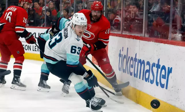 Carolina Hurricanes' William Carrier (28) clears the puck past Seattle Kraken's Jacob Melanson (63) during the first period of an NHL hockey game in Raleigh, N.C., Saturday, Jan. 10, 2026. (AP Photo/Karl DeBlaker)