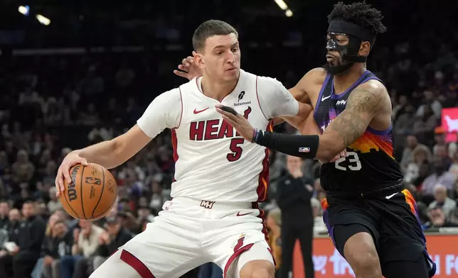 Miami Heat forward Nikola Jovic (5) shields the ball from Phoenix Suns guard Jordan Goodwin (23) during the first half of an NBA basketball game, Sunday, Jan. 25, 2026, in Phoenix. (AP Photo/Rick Scuteri)