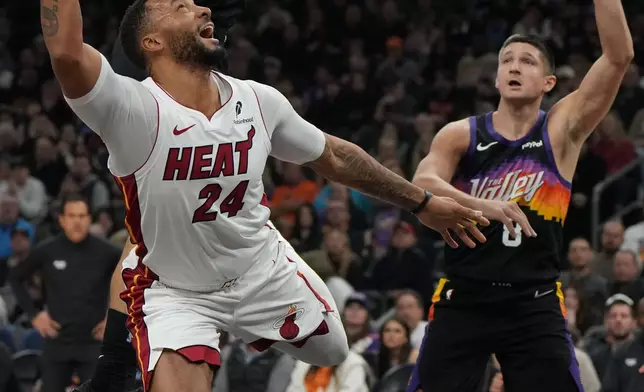 Miami Heat guard Norman Powell (24) drives between Phoenix Suns forward Dillon Brooks, top, and guard Grayson Allen, right, during the first half of an NBA basketball game, Sunday, Jan. 25, 2026, in Phoenix. (AP Photo/Rick Scuteri)