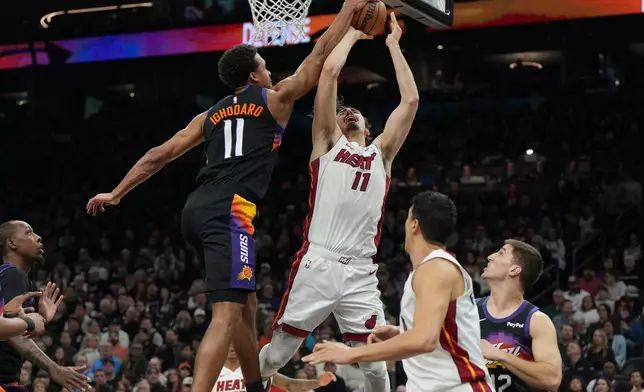 Phoenix Suns forward Oso Ighodaro, center left, blocks a shot by Miami Heat forward Jaime Jaquez Jr., center right, during the first half of an NBA basketball game, Sunday, Jan. 25, 2026, in Phoenix. (AP Photo/Rick Scuteri)