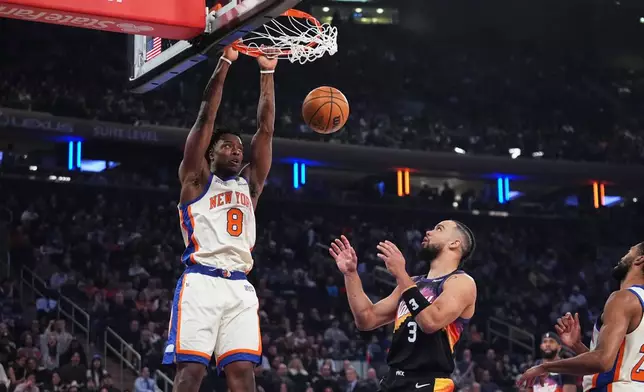 New York Knicks' Og Anunoby (8) dunks the ball in front of Phoenix Suns' Dillon Brooks (3) during the first half of an NBA basketball game Saturday, Jan. 17, 2026, in New York. (AP Photo/Frank Franklin II)