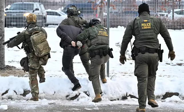 Federal agents confront protesters outside the Bishop Henry Whipple Federal Building, Thursday, Jan. 8, 2026, in Minneapolis, Minn. (AP Photo/Tom Baker)